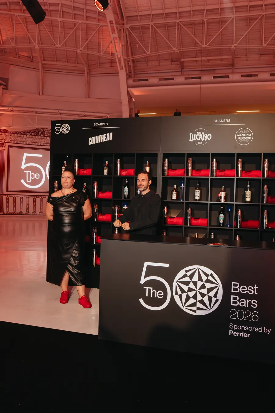 Cointreau bei The 50 Best Bars 2026: Regalwand mit roten Schals und Flaschen am Stand in Mailand