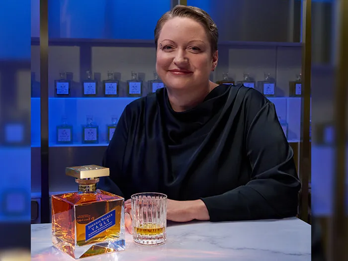 Dr. Emma Walker, Master Blenderin von Johnnie Walker, mit einer Flasche Johnnie Walker Vault an einem Tresen